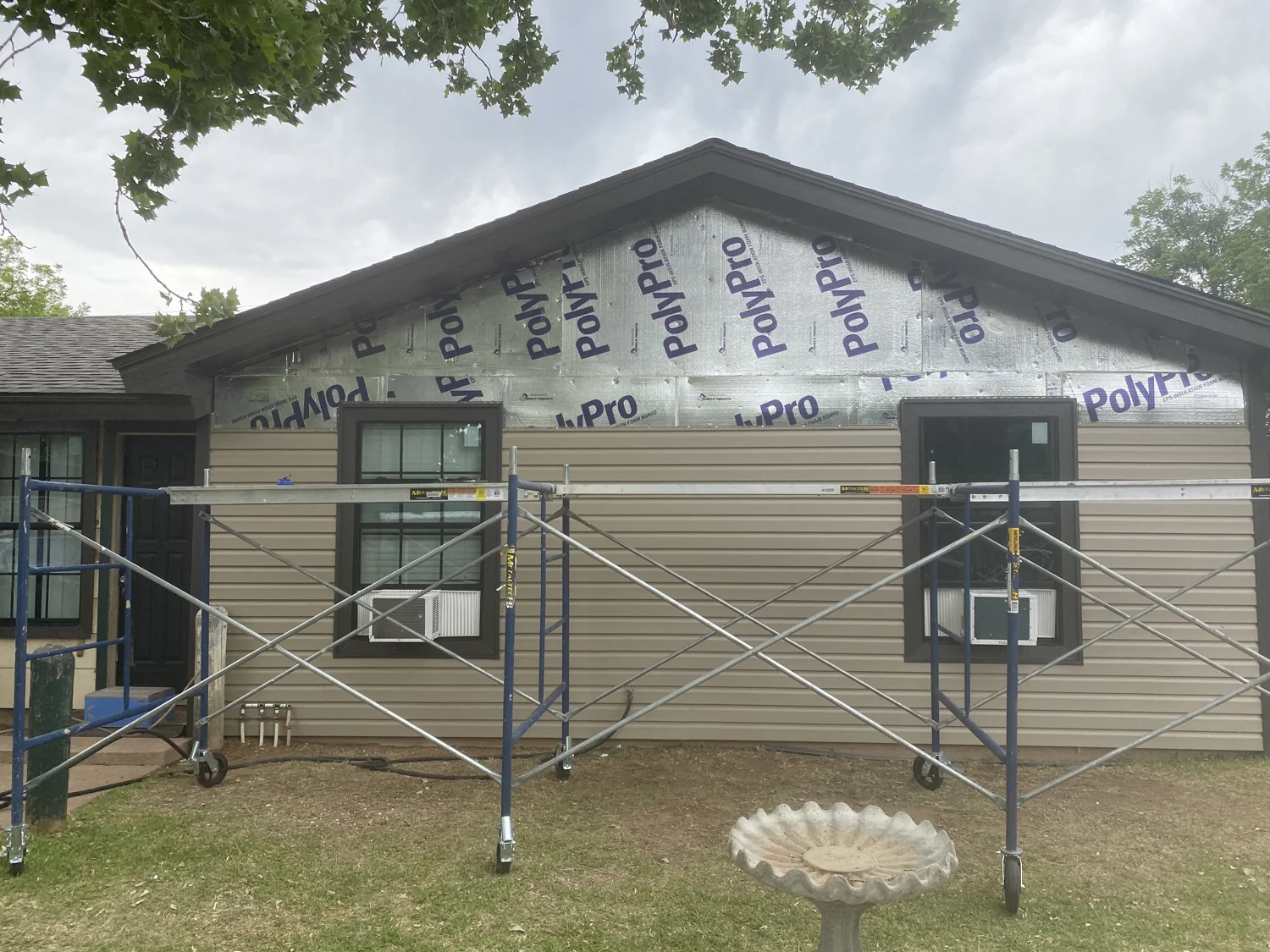 Scaffolding and vinyl siding installation in progress on a home