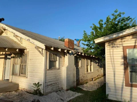 Original side exterior with worn siding and exposed roof-edge details.