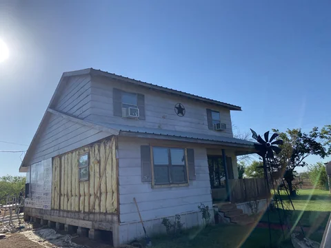 Two-story home with weathered siding and exposed sheathing before the exterior was finished.