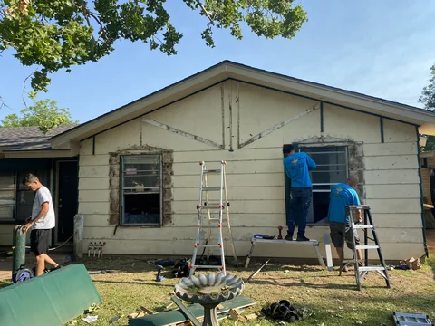 Crew members preparing the front exterior for new siding.