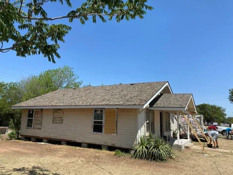Wider view of the same home’s siding project with work continuing near the porch.