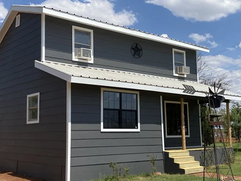 A closer view of the same home’s gray siding and white window trim.
